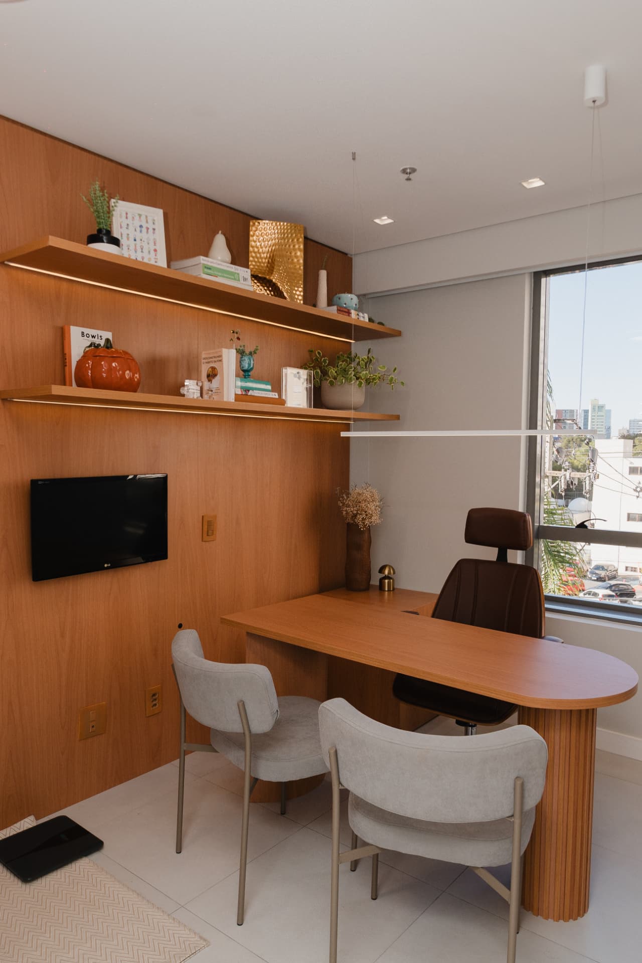 Consultório de Priscila Lara com mesa de atendimento e vista para Curitiba
